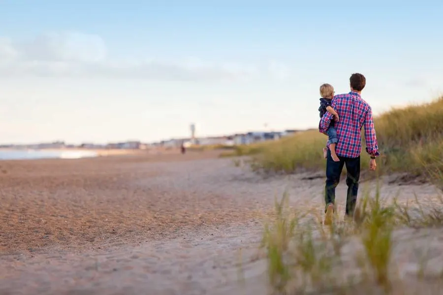 Amara and Theo walking on a beach at the end of the day