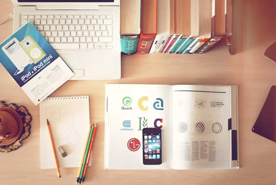 A desk with printed charts, a laptop and a notebook