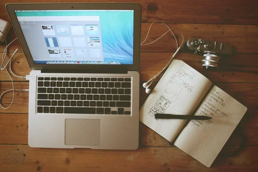 A laptop and an open notebook on a wooden table
