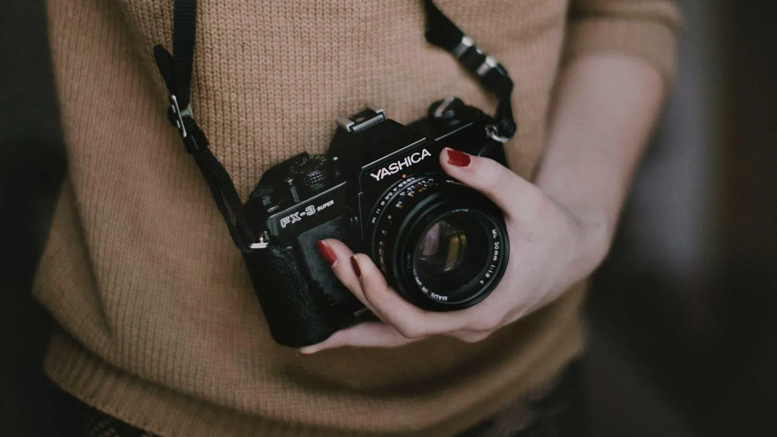 A photographer holding a camera at waist height in warm evening light