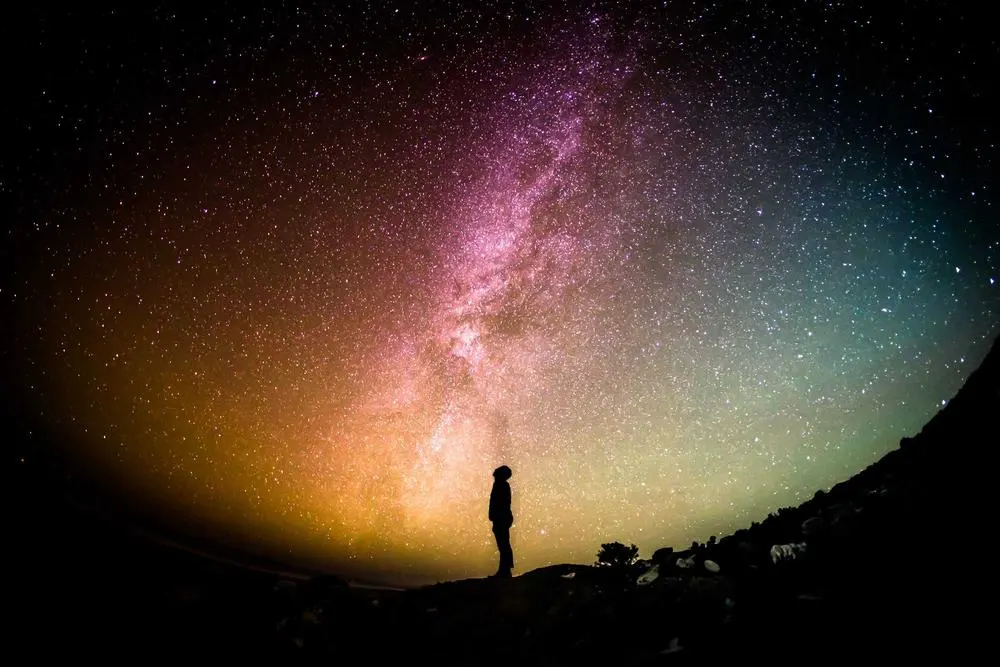 A person under the Milky Way on a dark hillside