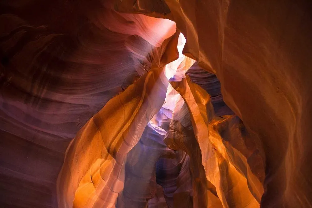 Orange sandstone walls of a slot canyon lit from above