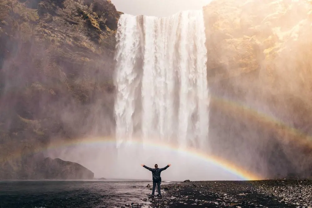 A tall waterfall with a rainbow in its spray
