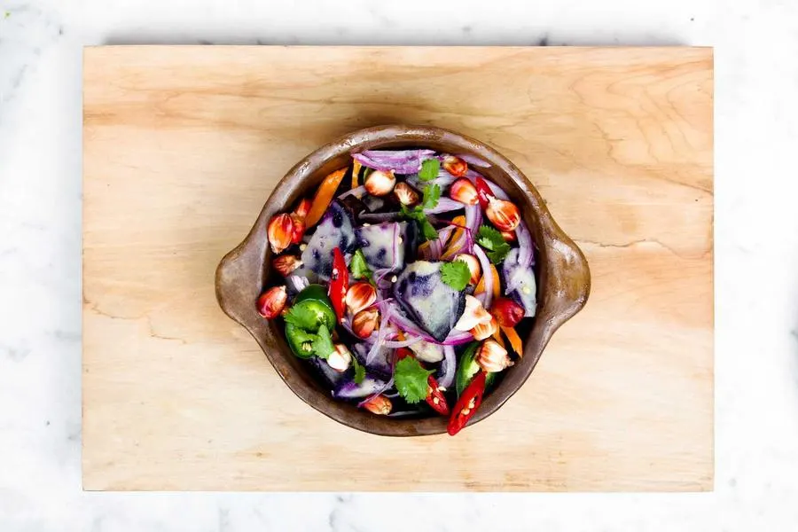A colourful salad bowl with burrata and peach on a marble table