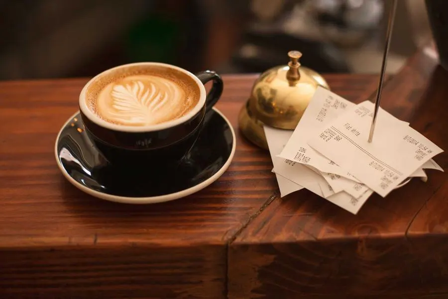 A flat white and handwritten notes on a wooden table