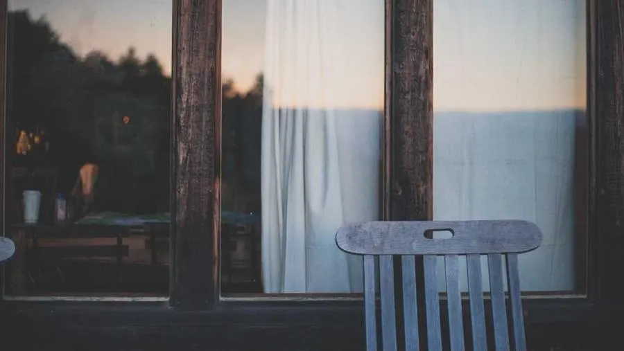 A calm white room with a chair by the window